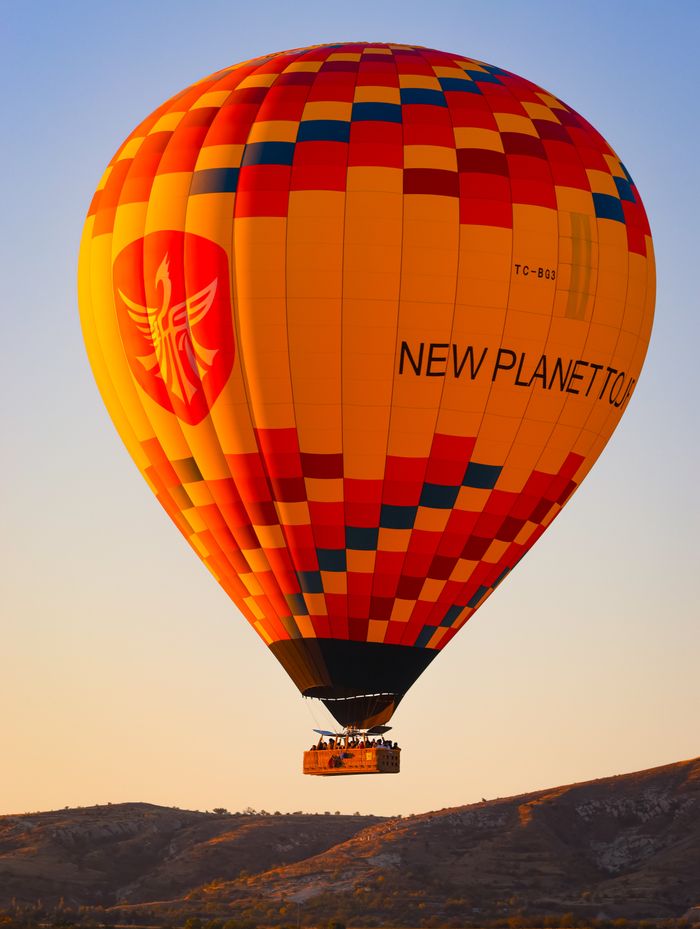 services-02 A vibrant hot air balloon soars over the unique landscape of Cappadocia during sunrise.