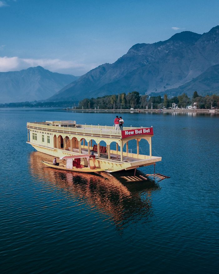 services-03 A vibrant houseboat on Dal Lake with stunning mountain backdrop, perfect for travel and leisure.